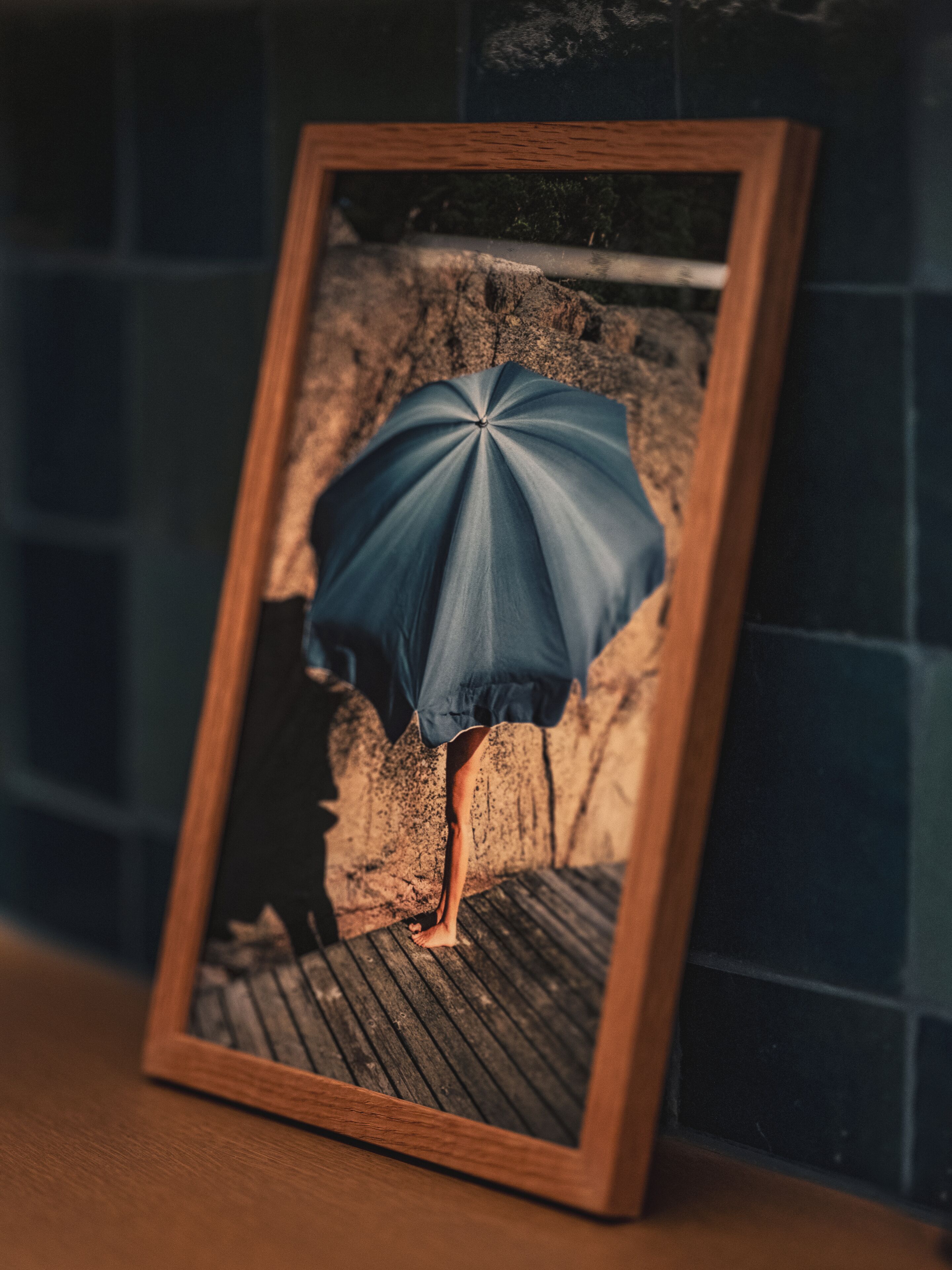 A framed photograph of a person standing under an umbrella.