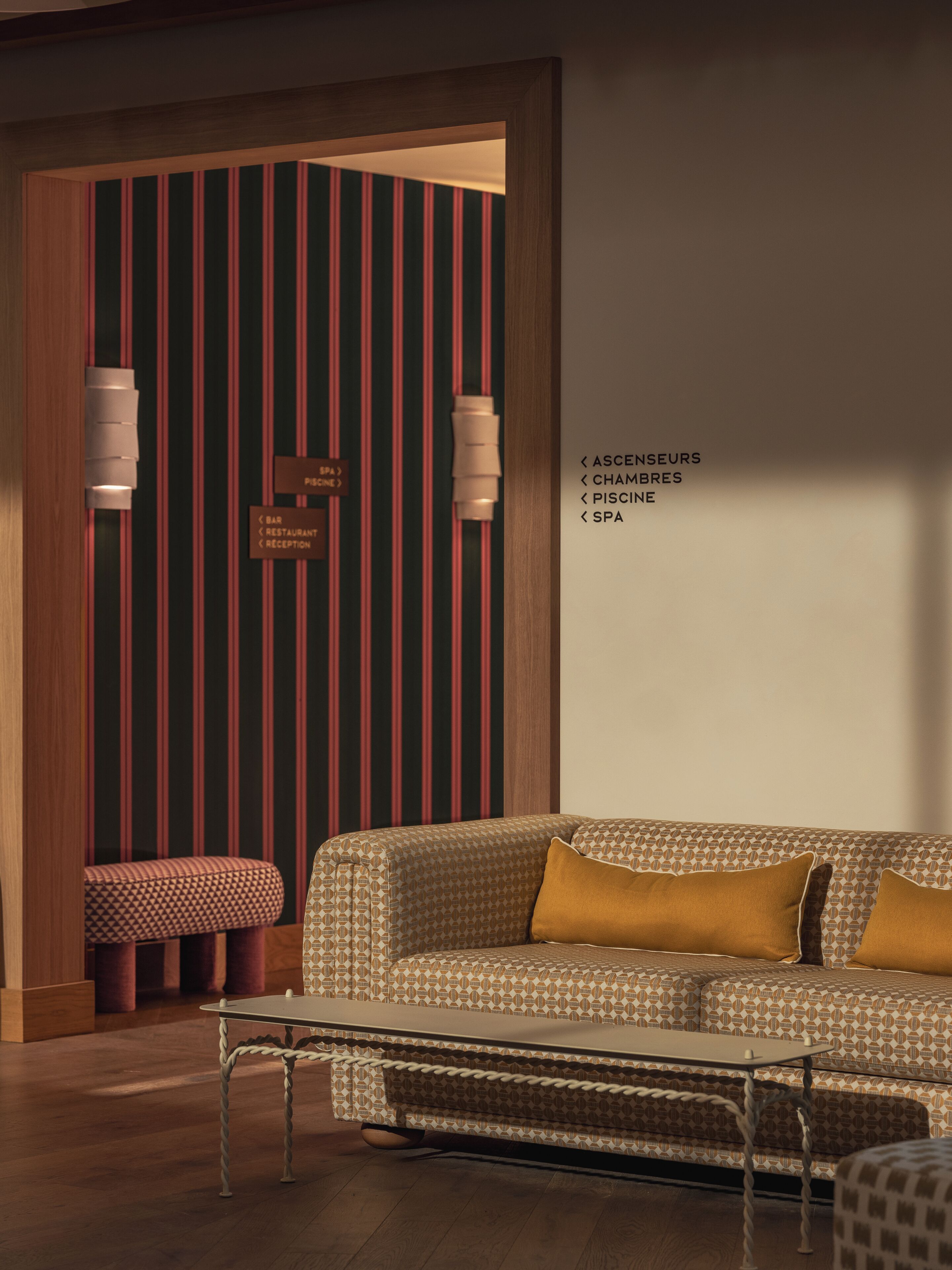 Een modern interieur met een gestreepte muur, een bank, een lange hocker en een tafel.