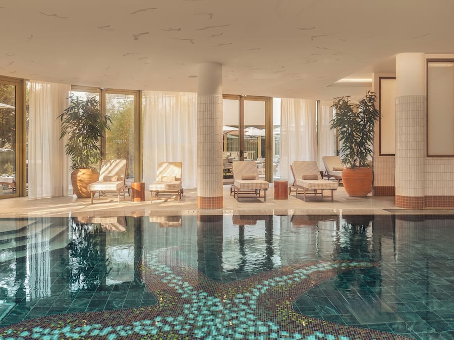 Uma piscina com piso ladrilhado e espreguiçadeiras.