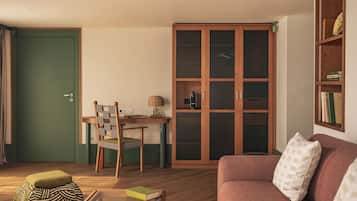 A cozy living room with a sofa, a dining table with chairs, a bookshelf, and a green door.