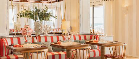 A dining area with striped seating, a central table, and hanging plants.