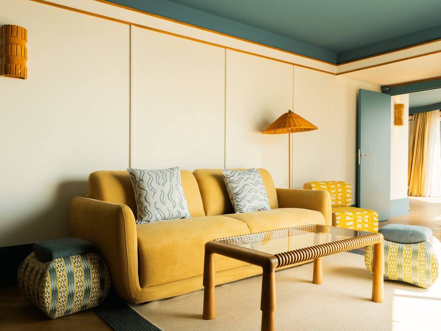 A living room with a sofa, ottomans, a coffee table, and a hanging lamp.