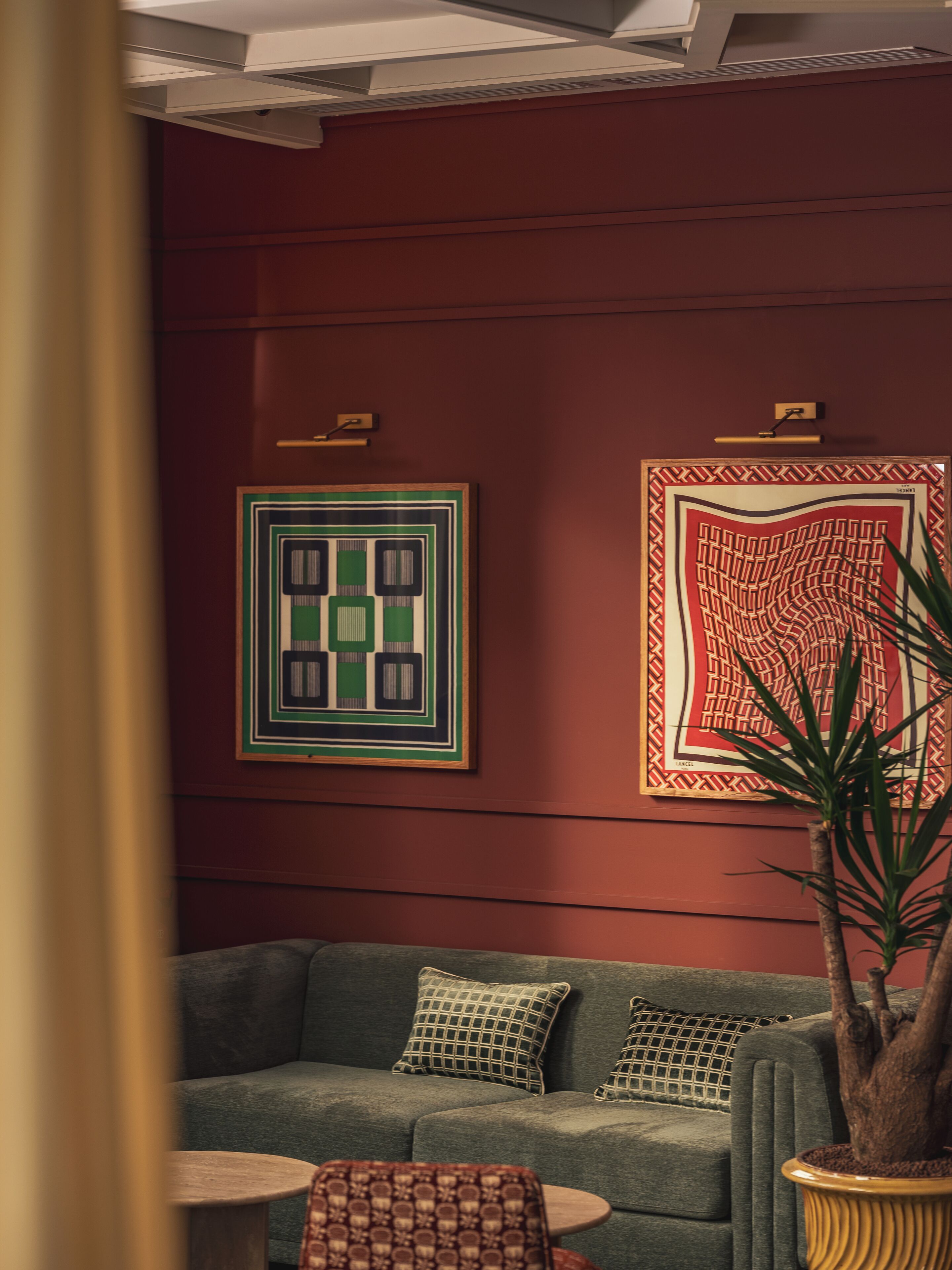 A room with a green sofa, a small round table, and a potted plant.