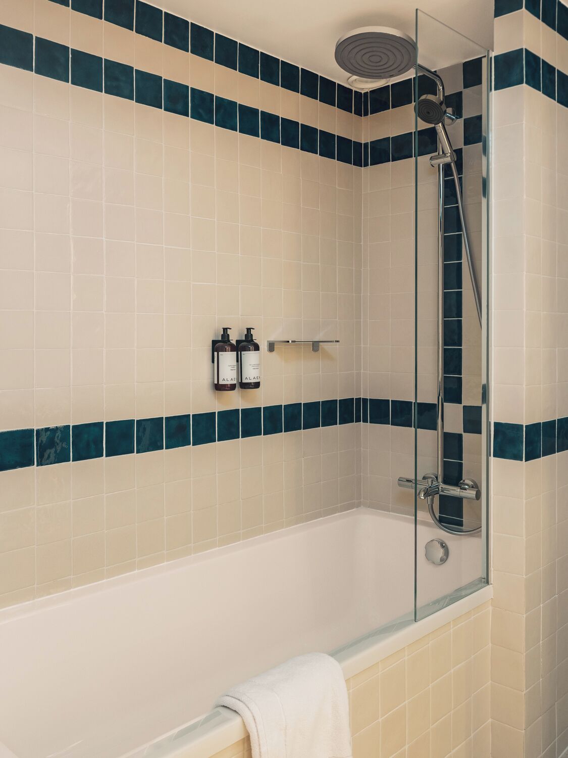 A modern bathroom with a glass-enclosed shower, a white bathtub, and a towel rack.