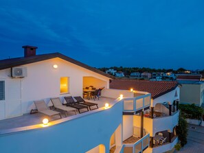 Un immeuble résidentiel doté d’une terrasse sur le toit, d’un espace extérieur aménagé et d’une piscine.