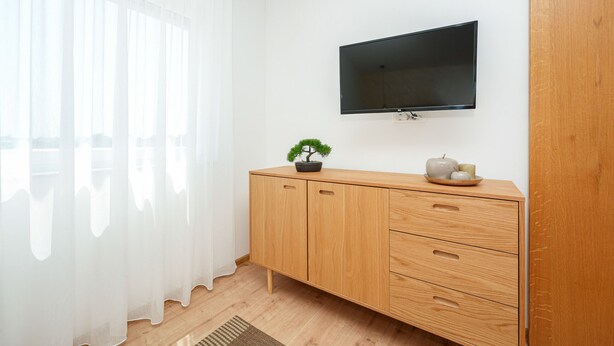 Ein modernes Zimmer mit einem Holzkasten, einem an der Wand montierten Fernseher und einem Blumentopf.