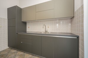 Eine moderne Küche mit eingebautem Spülbecken, grauen Schränken und einer gefliesten Rückwand.