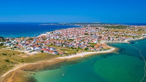 Luftaufnahme einer Küstenstadt mit einer dichten Bebauung, einem Strand und klarem, blauem Wasser.