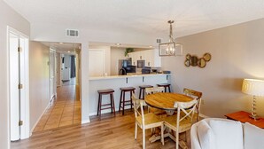 A modern kitchen with white cabinets, a central island, and bar stools. - Golf lovers’s condo with golf, 11 pools, hot tubs, gym, tennis, pickleball, W/D (Panama City Beach)