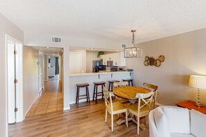 A modern kitchen with white cabinets, a central island, and bar stools. - Golf lovers’s condo with golf, 11 pools, hot tubs, gym, tennis, pickleball, W/D (Panama City Beach)