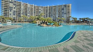 A large hotel with a swimming pool and palm trees. - Golf lovers’s condo with golf, 11 pools, hot tubs, gym, tennis, pickleball, W/D (Panama City Beach)