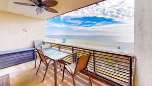 A balcony with a table and chairs, overlooking a beach. - Coastal Gem w/ Beach & Pool Access, Oceanfront Views from Balcony, and Netflix (Panama City Beach)
