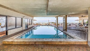 An indoor pool area with clear glass walls, a brick floor, and a view of the sky. - Coastal Gem w/ Beach & Pool Access, Oceanfront Views from Balcony, and Netflix (Panama City Beach)