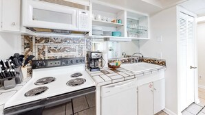 A kitchen with a white stove, a coffee maker, and a sink. - Coastal Gem w/ Beach & Pool Access, Oceanfront Views from Balcony, and Netflix (Panama City Beach)