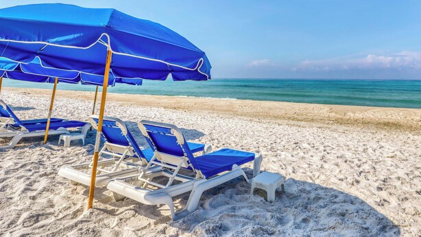 A beach with blue umbrellas and white lounge chairs. - Coastal Gem w/ Beach & Pool Access, Oceanfront Views from Balcony, and Netflix (Panama City Beach)