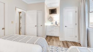Ein Schlafzimmer mit Bett, Kommode, Spiegel und einem Vorhangfenster.