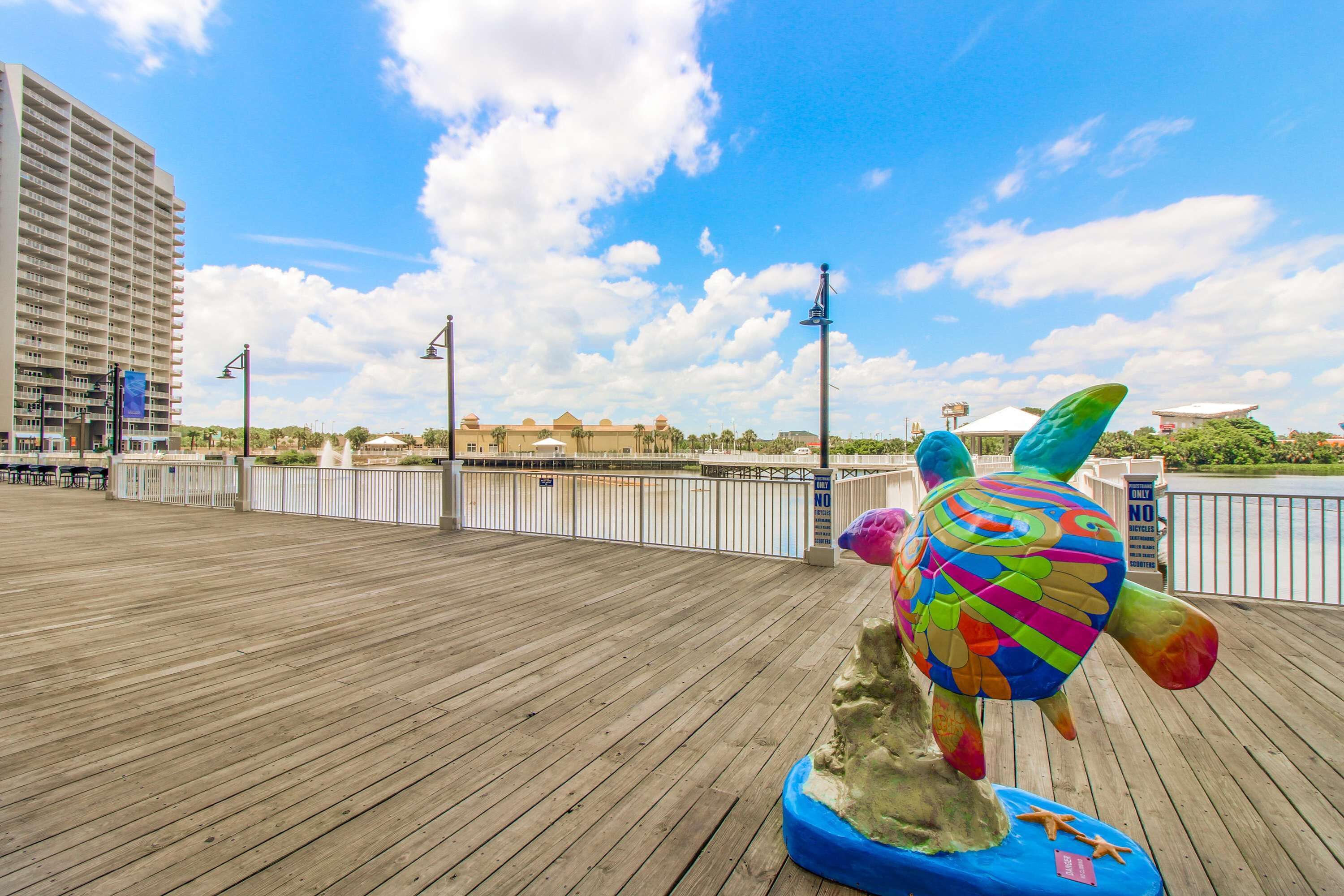 A wooden deck with a colorful turtle sculpture, a tall building, and a clear blue sky.