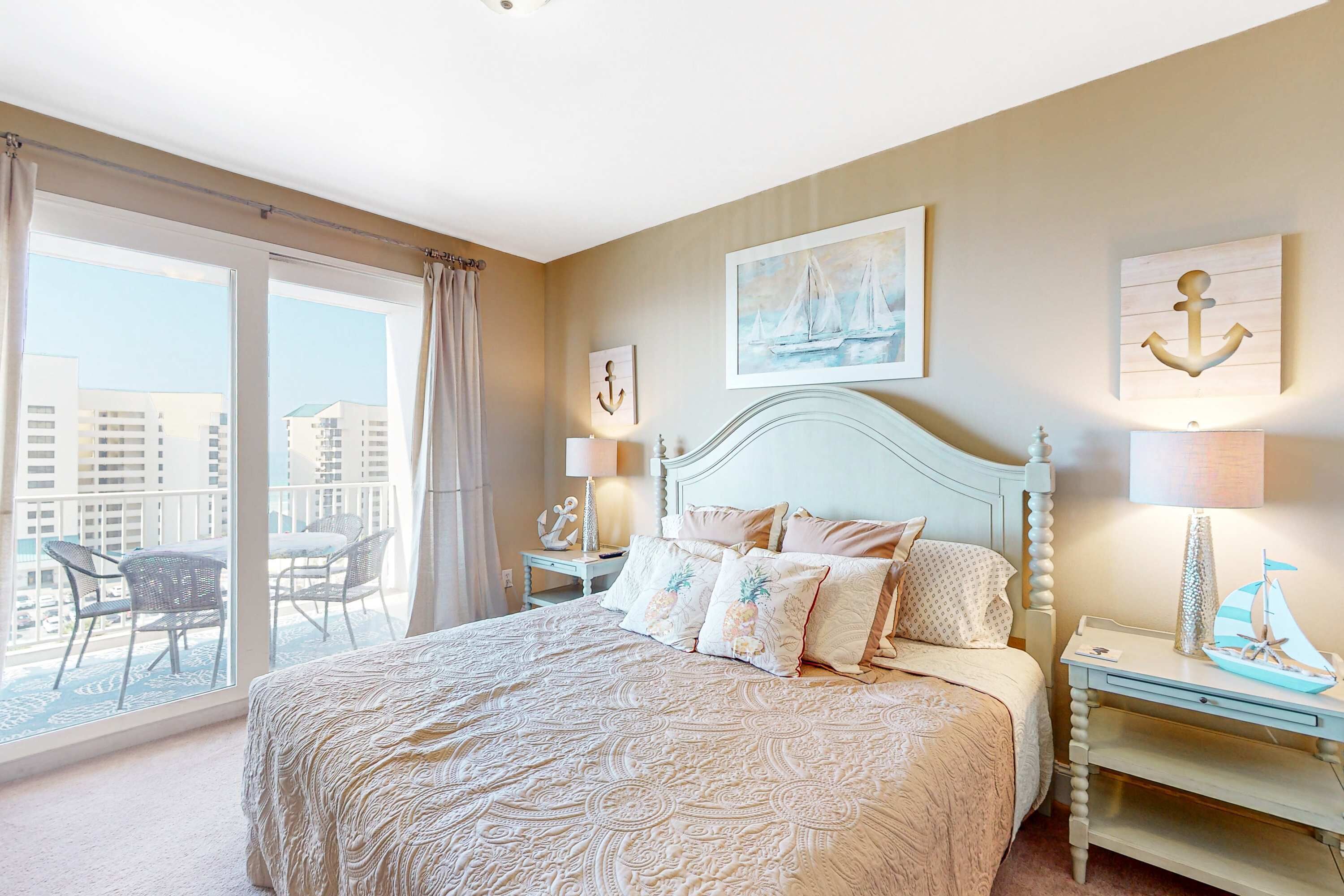 A bedroom with a large bed, a balcony with chairs, and nautical-themed decor.
