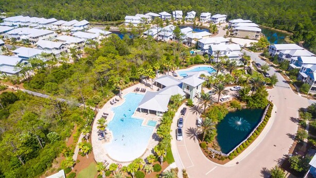 Luchtbeeld van een resort met meerdere gebouwen, een centraal zwembad en een kleiner, rond zwembad.