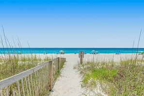 A beach path leading to the ocean with a wooden fence on one side and beach umbrellas on the other. - Dog-friendly home steps to beach with 2 kitchens, dressing room & game room (Panama City Beach)