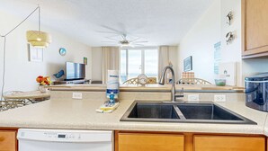 A modern kitchen with a dishwasher, double sink, and a ceiling fan. - 7th-floor bright, open condo - close to dining with Gulf front views (Navarre Beach)