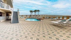 A pool area with a staircase, lounge chairs, and a palm tree. - 7th-floor bright, open condo - close to dining with Gulf front views (Navarre Beach)