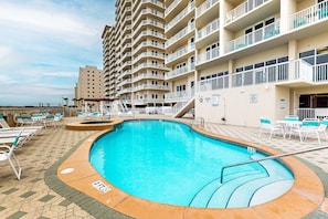A swimming pool with a 3ft depth marker, surrounded by lounge chairs and a multi-story building with balconies. - 7th-floor bright, open condo - close to dining with Gulf front views (Navarre Beach)