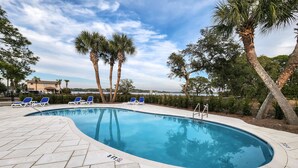 A swimming pool with blue water, surrounded by palm trees and lounge chairs. - Relaxing retreat with Lake Powell views, dock access, 2 pools, & screened patio (Panama City Beach)