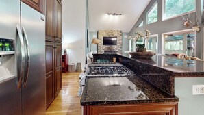 A modern kitchen with stainless steel appliances, a granite countertop, and a stone backsplash. - Mountain Home Dog-friendly Getaway (Cashiers)