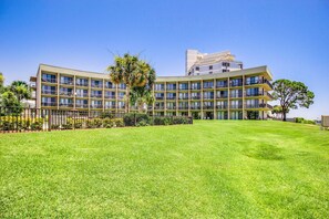 A multi-story hotel with a flat roof, large windows, and a well-maintained lawn. - Cozy soundfront studio with shared pool, beach access & close to everything (Fort Walton Beach)