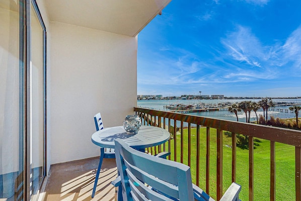 A balcony with a table and chairs, overlooking a marina with boats and a pier.