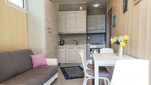 Ein kompakter Wohnbereich mit Sofa, Esstisch und Stühlen, einer Küchenzeile mit Schränken und einem kleinen Teppich.