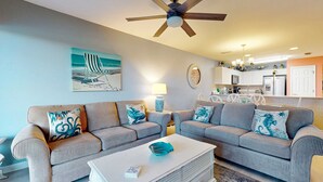 Ein Wohnzimmer mit gestreiften Sofas, einem weißen Couchtisch und einem Deckenventilator.