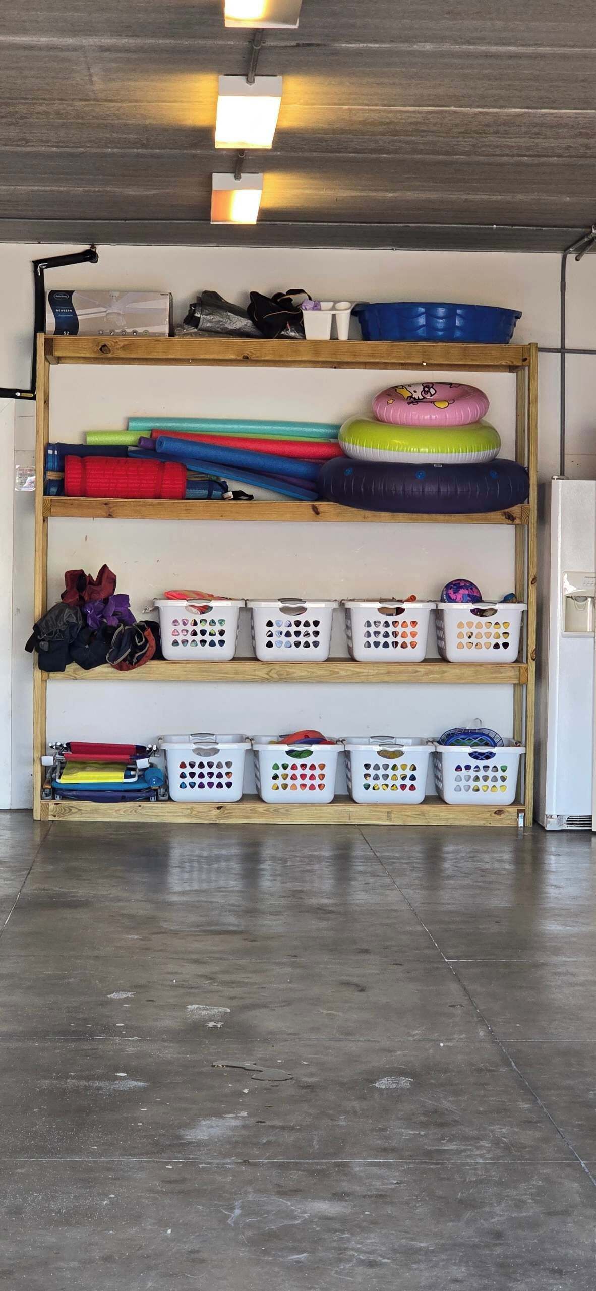 A storage area with shelves holding various items including laundry baskets, a sewing machine, and a stack of colorful mats.