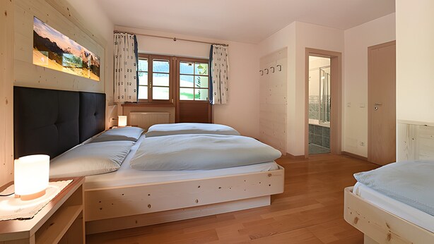 A bedroom with a bed, bedside table, window with curtains, and a view of the outside. - Villa Konstanze Apartment with Mountain View, Private Terrace and Wi-Fi (Plan Da Tieja)