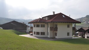 A two-story house with a red roof, a balcony, and a driveway leading to a parked car. - Villa Konstanze Apartment with Mountain View, Private Terrace and Wi-Fi (Plan Da Tieja)