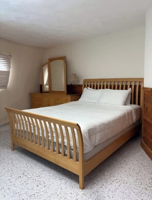 A single-bed room with a wooden headboard, a bedside table, a mirror, and a wardrobe. - Unique waterfront home with wraparound deck and private grill - free WiFi (Cape San Blas)