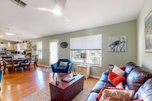 Ein geräumiges Wohnzimmer mit Essbereich, einem blauen Sessel, einer Ledersofa und einer Küche im Hintergrund.