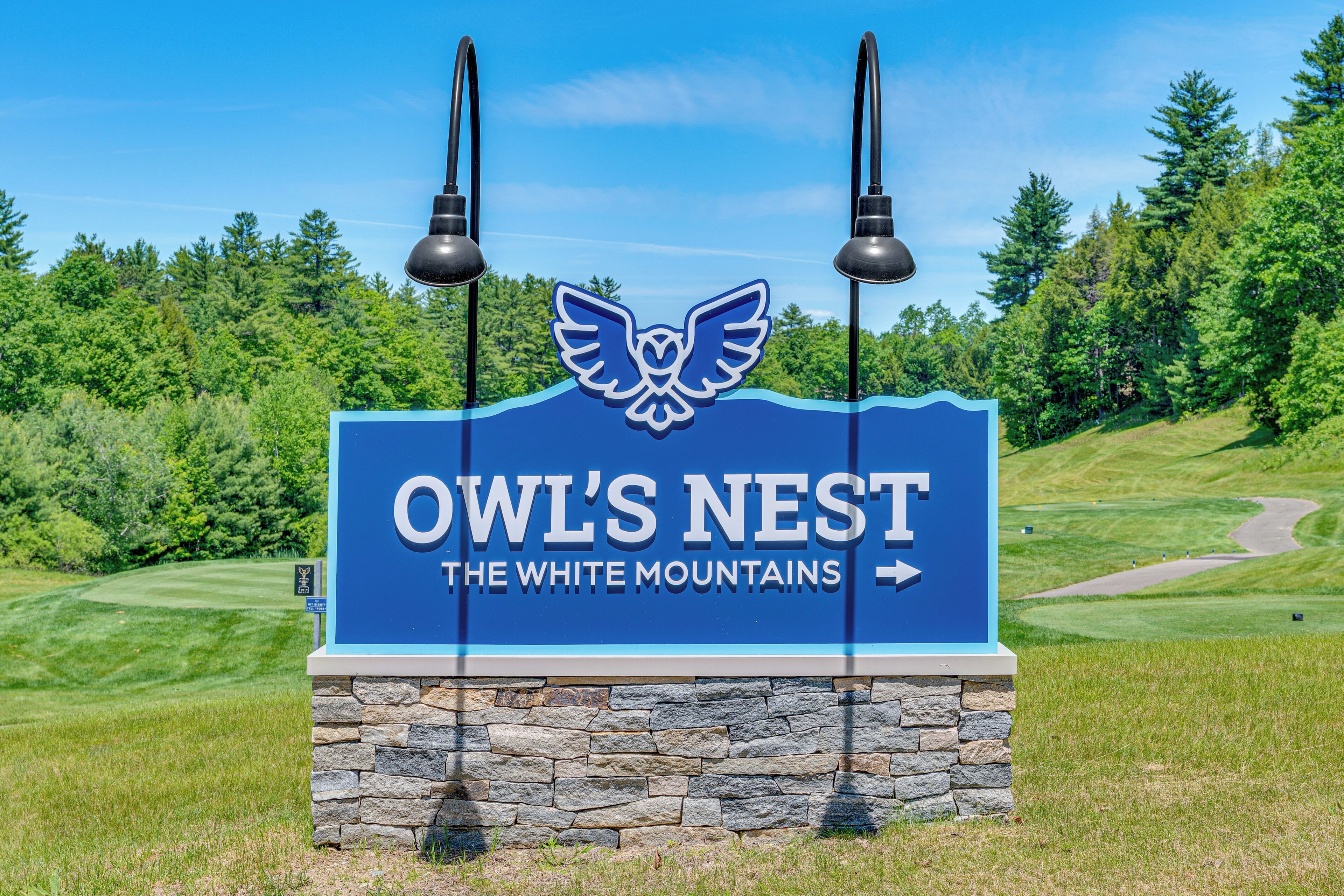 Naambord voor 'OWL'S NEST THE WHITE MOUNTAINS' met een stenen voetstuk en twee zwarte lampen.
