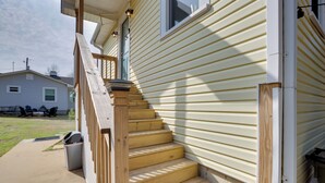 Un escalier en bois mène à une maison dont le revêtement extérieur est constitué de planches disposées horizontalement.