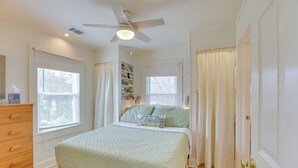 Une chambre à coucher comprenant un lit, une commode, un ventilateur de plafond et une bibliothèque.