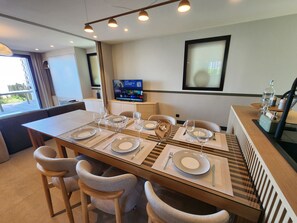 Un coin repas avec une table en verre, des sets de table à rayures et des chaises en osier.