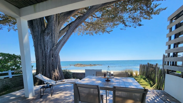 A wooden deck with a table and chairs, overlooking a beach and ocean. - VILLA BEAUMER - Beach Access . Sea view - TK60 (Carnac)