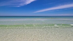 Una platja amb aigües poc profundes i transparents sota un cel serè.