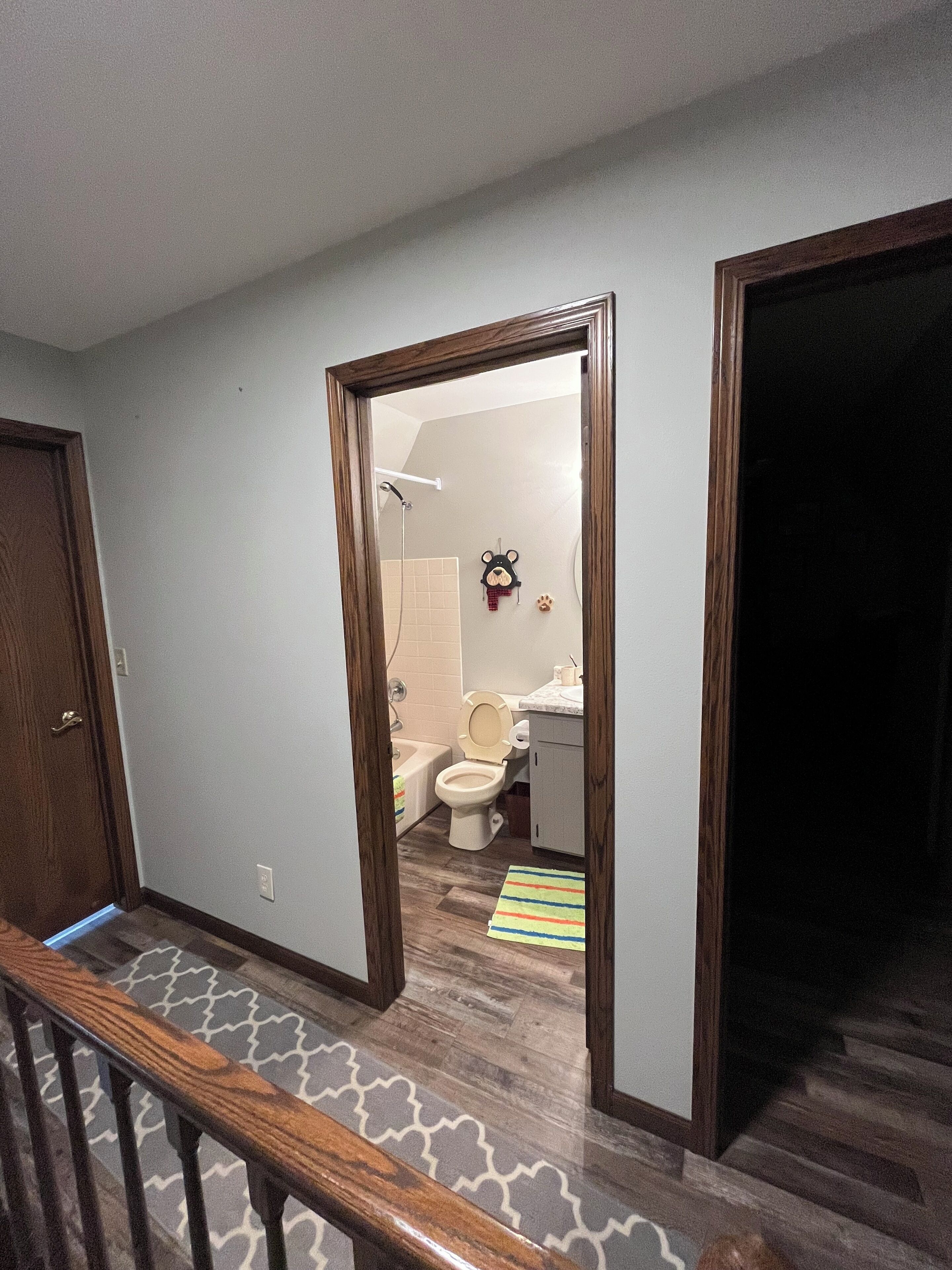 Un pasillo que conduce a un baño con inodoro, ducha y un lavamanos pequeño.