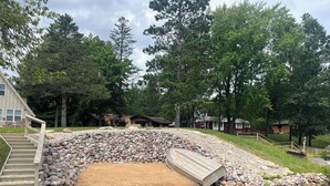 Une propriété au bord du lac, dotée d’un quai en bois, d’un sentier en pierre et d’un petit bateau.