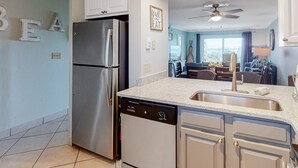 A modern kitchen with a stainless steel refrigerator, a dishwasher, and a granite countertop.