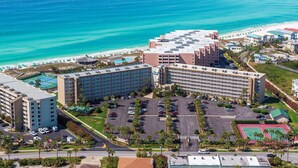 A resort with multiple hotel buildings, a parking lot, and a beach area.
