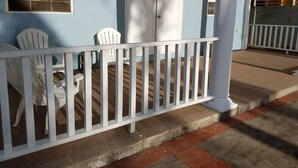 Eine Veranda mit weißer Holzvertäfelung, zwei weißen Stühlen und einer weißen Tür.