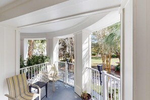 A covered porch with white railings, two chairs, and a potted plant. - 2nd-floor resort condo with balcony, on-site pool, golf, tennis & beach access (Miramar Beach)